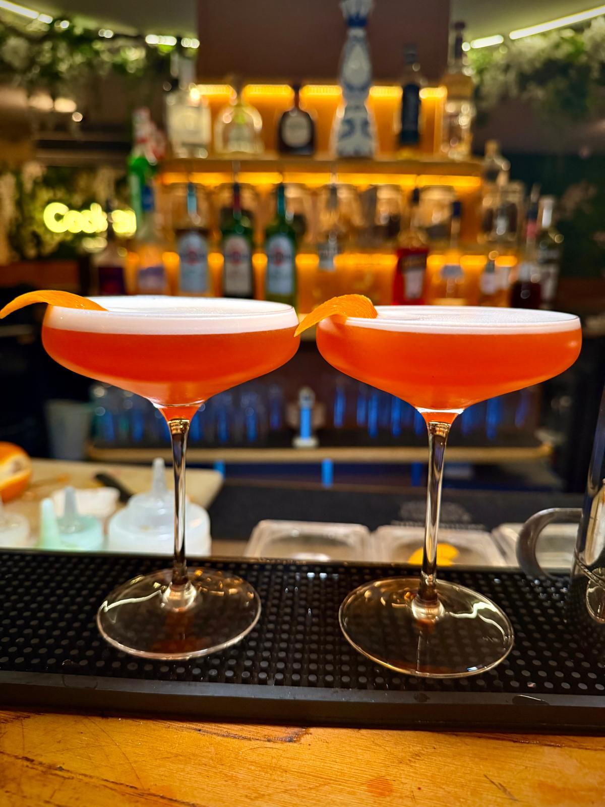 Deux cocktails orange au zeste, servis au comptoir